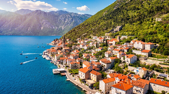 View of the historic town of Perast at famous Bay of Kotor on a beautiful sunny day with blue sky and clouds in summer, Montenegro. Historic city of Perast at Bay of Kotor in summer, Montenegro.