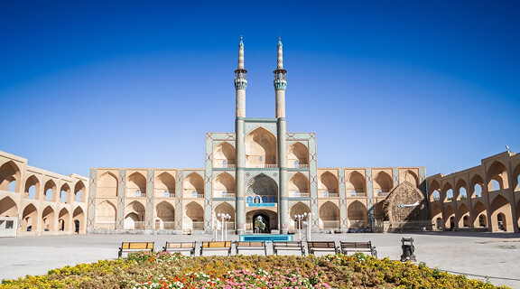 Wide view of Amir Chakhmaq complex in Yazd, Iran, with its arched facade, turquoise tilework and twin minarets facing the main square, an iconic Shia Islamic landmark and symbol of the desert city.
