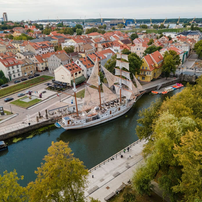 An aerial view of cityscape Klaipeda surrounded by buildings with floating boats on Danes river