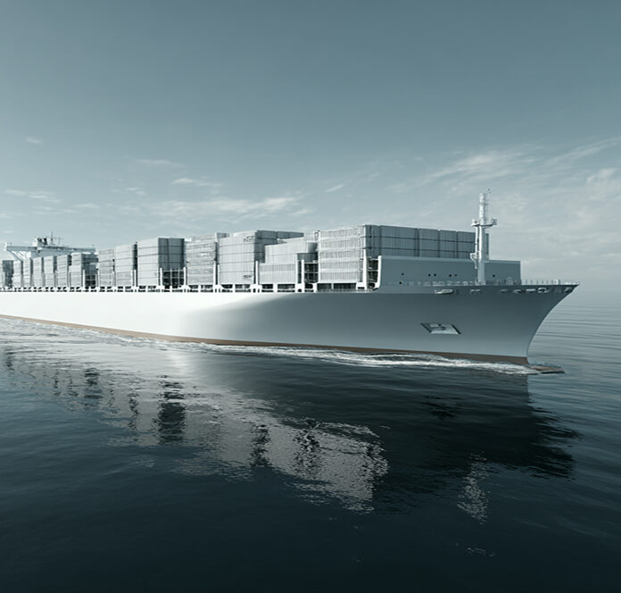 A large cargo ship loaded with stacked shipping containers sails across calm ocean waters under a partly cloudy sky.
