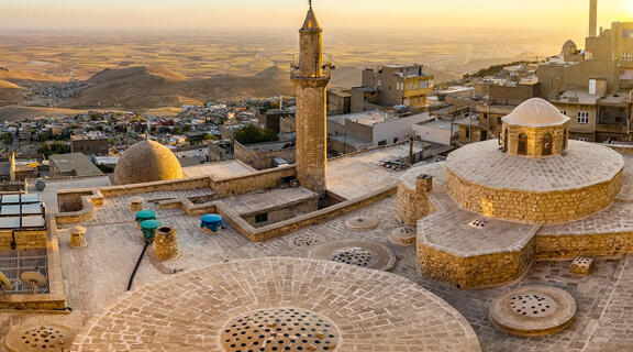 Cityscape panorama old Mardin town at sunset, capital of Mardin Province in southeastern Turkey. Old town of Mardin with roof of a traditional Turkish hammam and minarets at sunset