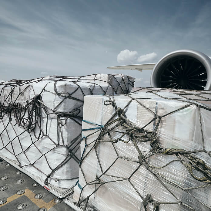 Preparation before flight. Loading of cargo containers against jet engine of freight airplane.