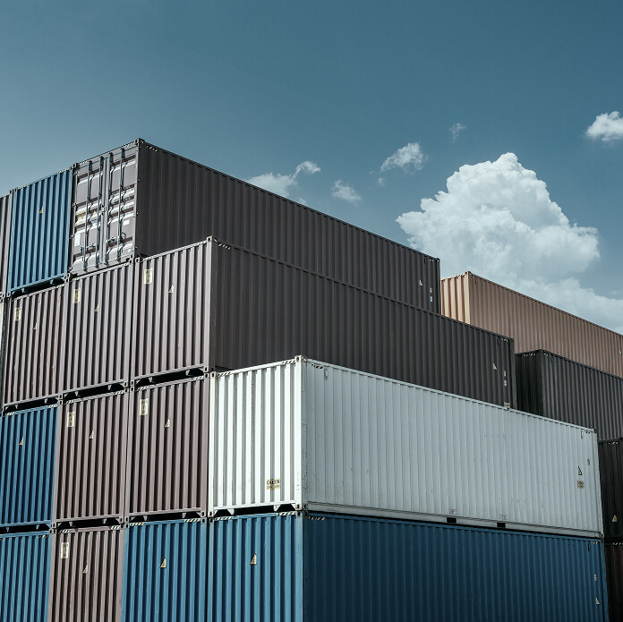 Colorful cargo containers stacked in a port yard under a clear blue sky, showcasing global trade and logistics infrastructure.